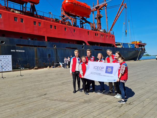 Expedition crew members on the quayside, holding a project banner